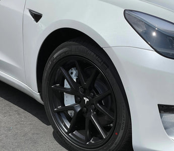 Front view of a white Tesla car showcasing its sleek wheel design and modern aesthetics