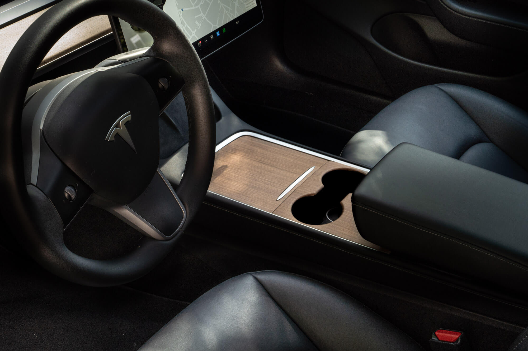 A modern Tesla car interior showcasing a spacious cabin with a large touchscreen and premium materials