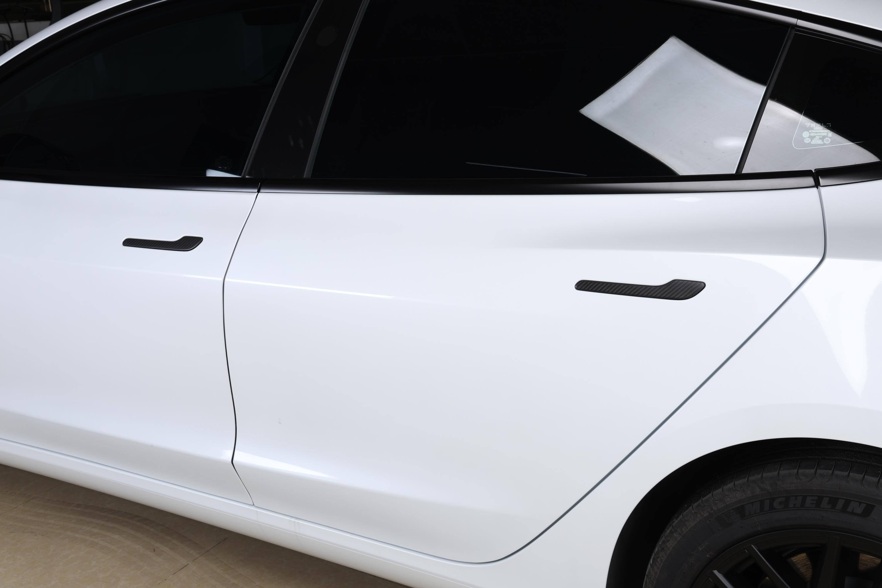 A close-up view of the side door of a white car featuring sleek black wheels